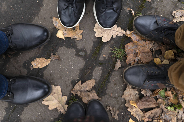 Four pairs of legs in boots and sneakers on the pavement against - Valokuva, kuva