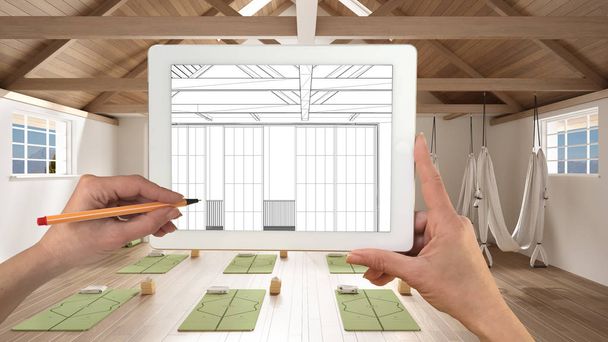 Kezek tartó és rajz tabletta mutatja üres jóga stúdió szőnyegek és kiegészítők Cad vázlat. Igazi befejezett belső tér a háttérben, építészet design bemutató - Fotó, kép