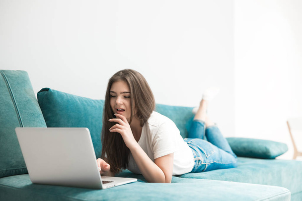 beautiful young woman watching film on her laptop lying on the sofa - Fotografie, Obrázek