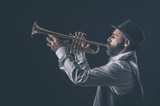 profile view of a jazz trumpet player with beard and hat. - Foto, Bild