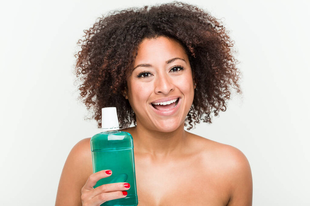 Young african american woman holding mouthwash happy, smiling and cheerful. - Photo, Image