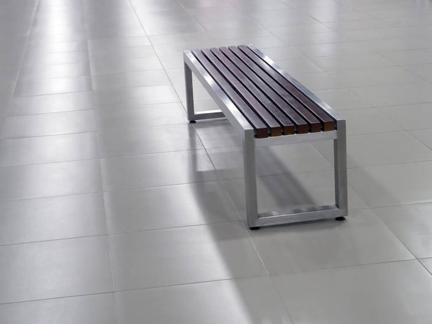 Banco con marco de acero y elementos de asiento de madera en el suelo de baldosas
 - Foto, imagen