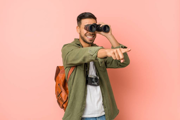 Young south-asian man looking through a binoculars. - Zdjęcie, obraz