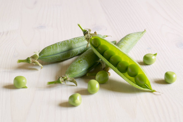 白い木製の背景に若い緑のエンドウ豆. - 写真・画像