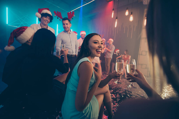 Фото вечеринки толпа лучших друзей, держащих игристые бокалы вина новогоднее праздничное настроение общения носить рубашки платья брюки Санта шляпа в ночном клубе
 - Фото, изображение