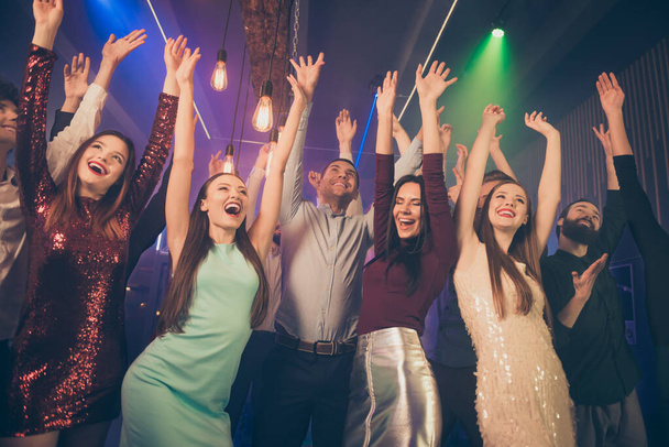 Фотографія багатьох партійних людей, які піднімають руки вгору, насолоджуючись Різдвяною ніччю, найкращі друзі, що горять на танцмайданчику, носять офіційний одяг розкішні сукні сорочки штани одяг
 - Фото, зображення