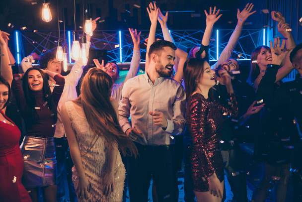 Photo of cheerful attractive beautiful students dressed in formalwear celebrating brithday of his friend surrounded by girls feeling carefree washed with neon light turned by dj - Foto, immagini