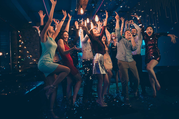Full length body size photo of company dancing cheerfully at night club under falling confetti and light of shining lamps with smiles on their faces - Фото, изображение