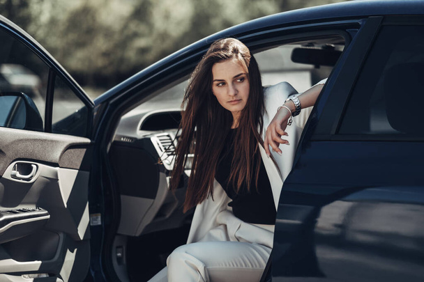 Divat stílusos lány fehér öltönyt jelentő közelében a kék autó - Fotó, kép