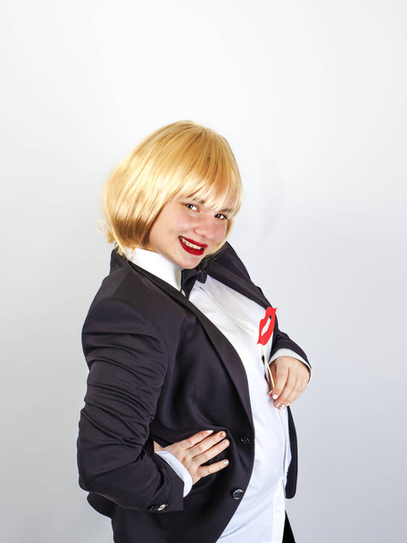 Elegant positive woman in dress coat with red paper lips on a stick on a gray background - Foto, afbeelding