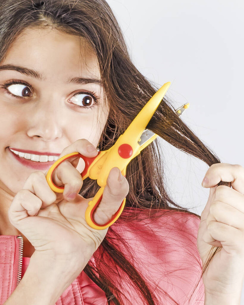 Une jeune fille est prête à se couper les cheveux avec des ciseaux
 - Photo, image