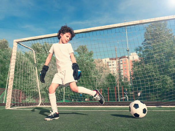 Boys in white sportswear running on soccer field. Young footballers dribble and kick football ball in game. Training, active lifestyle, sport, children activity concept. selective focus - 写真・画像