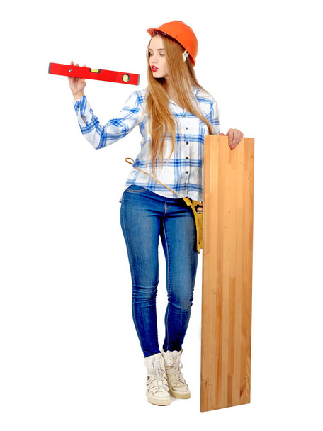 Happy attractive hardworking female worker with construction level and wooden board Isolated on white - Fotó, kép
