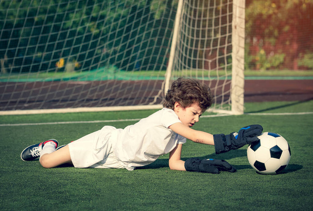 Young soccer goalie attempting to make a save. little soccer goalkeeper with gloves. Kids - soccer champion. Boy goalkeeper in football sportswear on stadium with ball. Sport concept. - Foto, Imagem