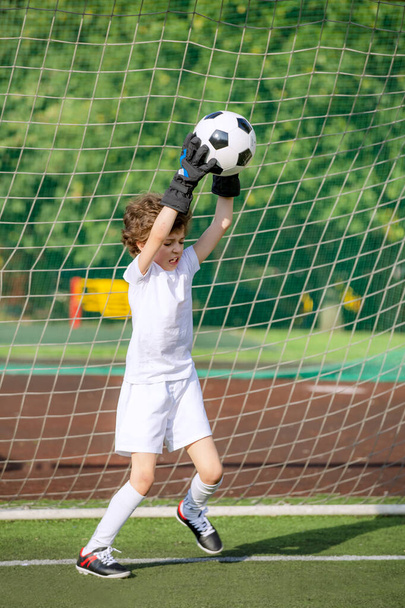 Summer soccer tournament for young kids. football club. emotions and joy of the game. Young goalie. Boy goalkeeper in football sportswear on stadium with ball. Sport concept. selective focus - Foto, Bild