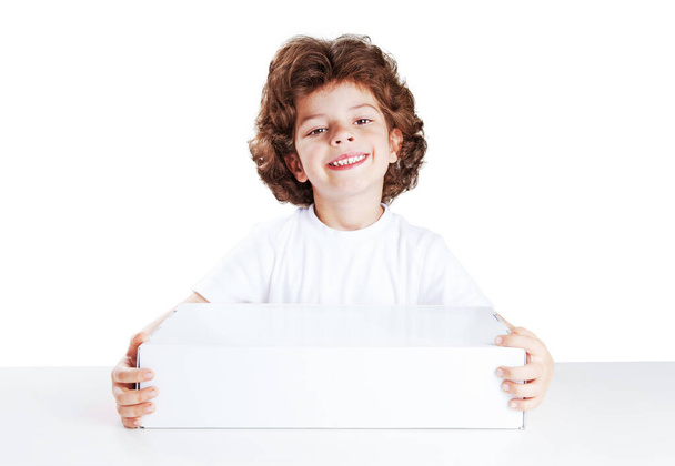 Cute curly-haired boy smiling presents a white box. Isolated on white. Close-up. - Foto, Imagem