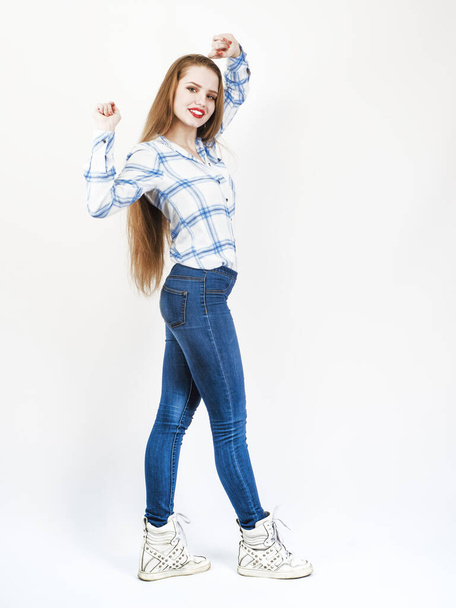 Beautiful happy woman posing white holding a collar of blue plaid shirt in jeans. Full body length standing over light background. - Fotó, kép