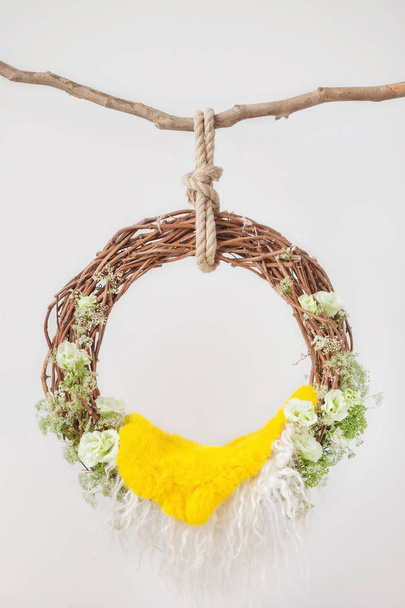 grape ring cradle for newborns on a white background, decorated with green flowers eustomas with a yellow rug, props for photographing newborn babies - Fotó, kép