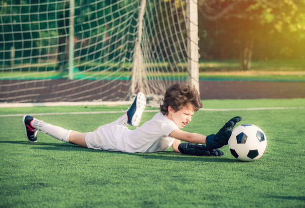 Young soccer goalie attempting to make a save. little soccer goalkeeper with gloves. Kids - soccer champion. Boy goalkeeper in football sportswear on stadium with ball. Sport concept. - Foto, Imagen