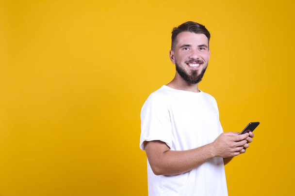 Perfectly groomed bearded man with fashionable hairstyle posing over yellow background. - Fotó, kép