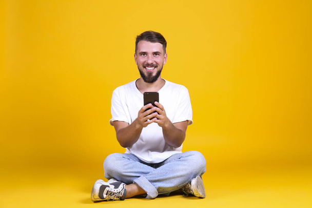 Perfectly groomed bearded man with fashionable hairstyle posing over yellow background. - Фото, зображення