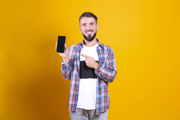 Perfectly groomed bearded man with fashionable hairstyle posing over yellow background. - Foto, Imagen