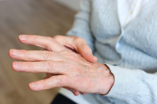 Close up shot of elderly woman's hands. Old lady wearing grey knitted cardigan. - Photo, Image