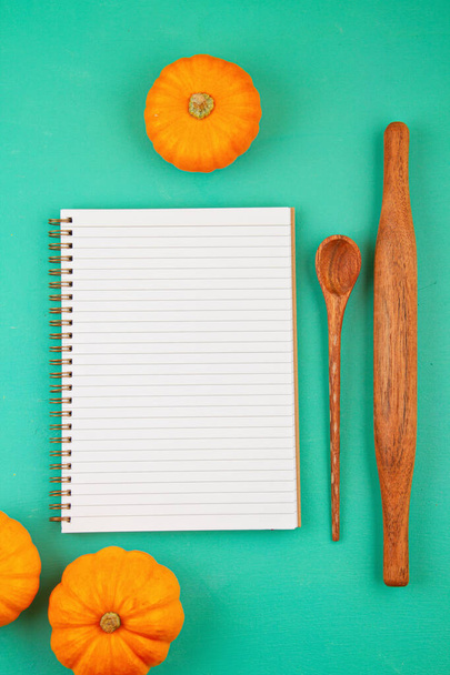 Яскраві помаранчеві гарбузи, кухонне начиння і порожня блокнот для списку покупок або рецепта
 - Фото, зображення