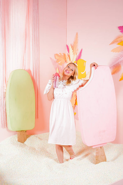 encantadora mulher loira feliz em um vestido de verão de renda suave posando com um enorme sorvete rosa na piscina com espuma de pequenas bolas macias e envolvidos em terapia de relaxamento
. - Foto, Imagem