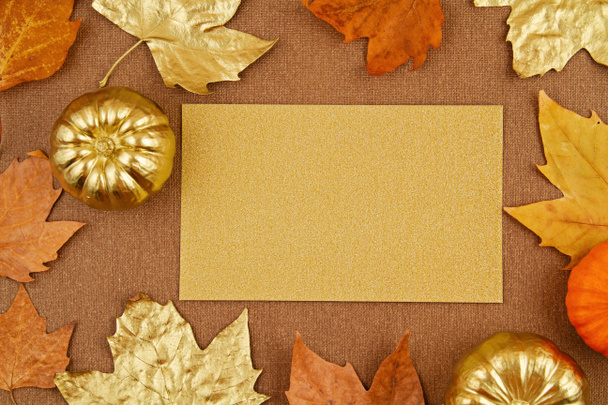 Platte herfstcompositie met vallende gele en gouden bladeren en pompoenen - Foto, afbeelding