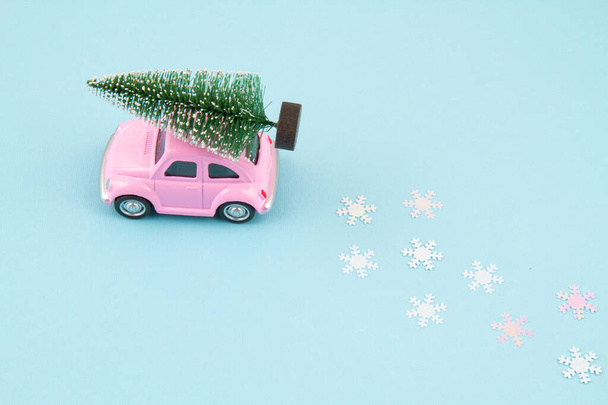 Small toy car carring christmas tree over the roof. Sesonal holidays, greeting card - Photo, Image