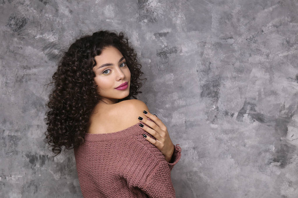 Beautiful woman with with light make up and curly hairstyle wearing distressed crop top sweater. - Φωτογραφία, εικόνα