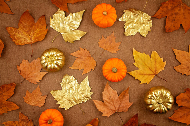 Плоская композиция осенью с осенью желтые и золотые листья и тыквы
 - Фото, изображение