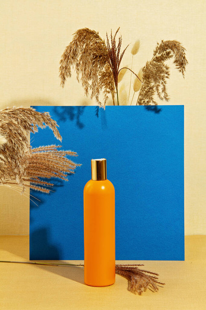 Background with autumn plants and bottle of cosmetic in pastel c - Foto, Bild