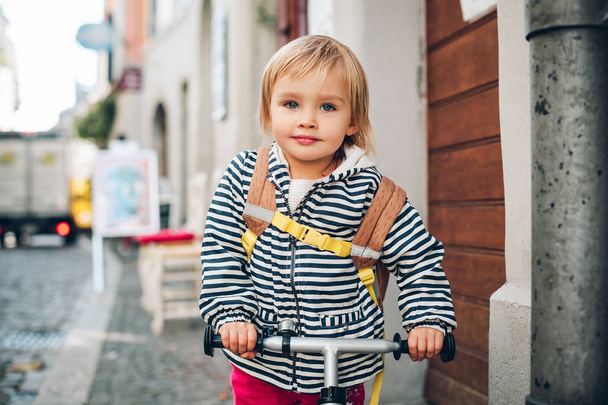 Retrato ao ar livre de uma menina pequena bonito, andar de bicicleta, usando mochila
 - Foto, Imagem