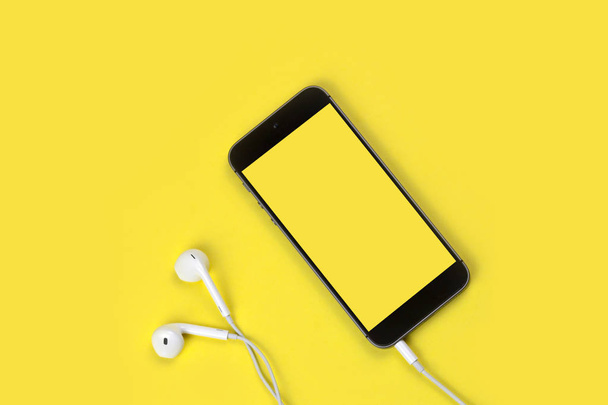 Έξυπνο τηλέφωνο και ακουστικά σε Freesia κίτρινο φόντο - Φωτογραφία, εικόνα