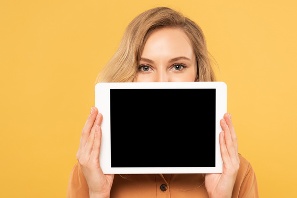 Blonde woman covering face with digital tablet with blank screen isolated on yellow - Foto, Bild