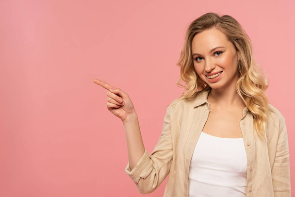 Smiling woman point with finger to side isolated on pink - Foto, immagini