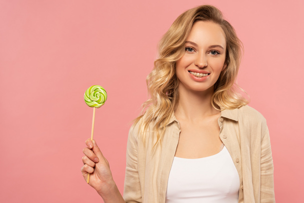 Smiling woman with dental braces holding lollipop isolated on pink - Fotoğraf, Görsel