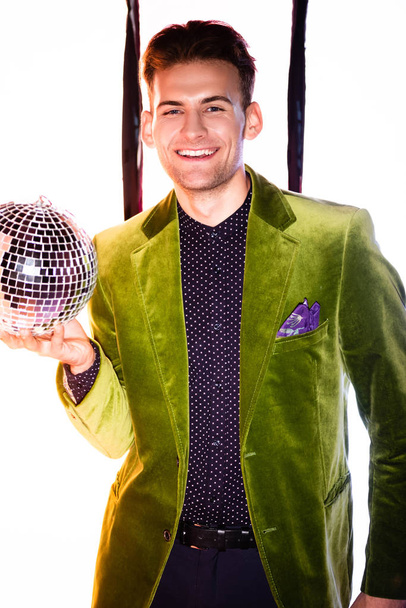 happy man in green blazer holding shiny disco ball on white with black stripes - Zdjęcie, obraz