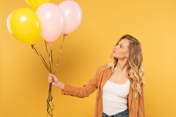 Blonde woman holding balloons isolated on yellow - Photo, Image