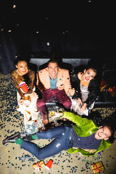 overhead view of cheerful multicultural friends holding drinks near disco ball  - Fotó, kép