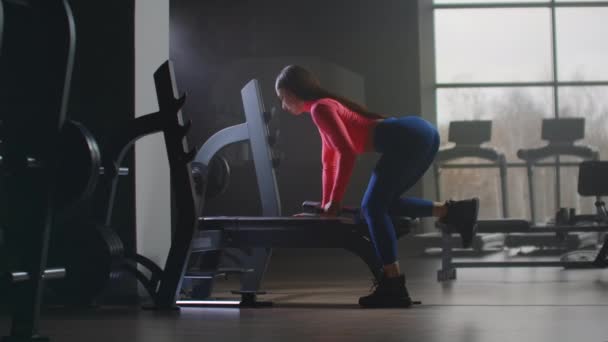 La joven está entrenando a su espalda en el banco
 - Metraje, vídeo