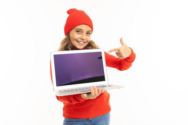 可愛いです女の子で赤いセーターと帽子ポージングでラップトップで白い背景  - 写真・画像