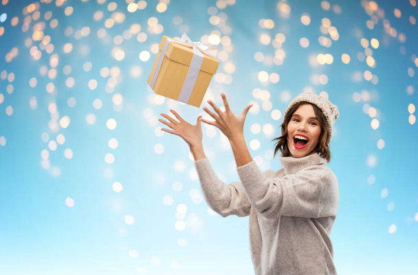 young woman in winter hat catching gift box - Фото, изображение