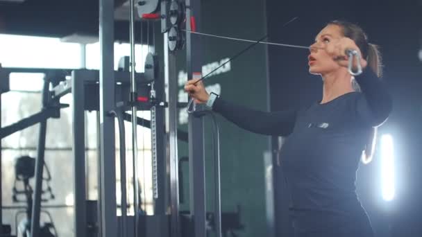 The woman shakes the muscles of the chest and arms in the gym - Footage, Video