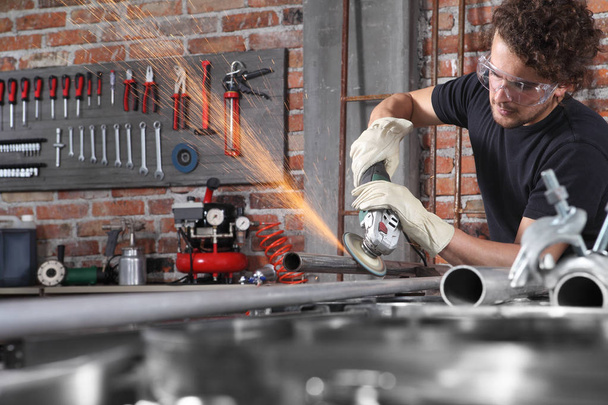 man work in home workshop garage with angle grinder, goggles and - Photo, Image
