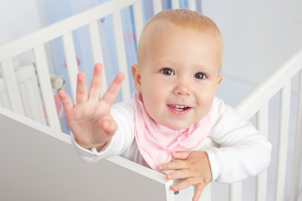 Retrato de um bebê bonito acenando Olá e sorrindo do berço
 - Foto, Imagem