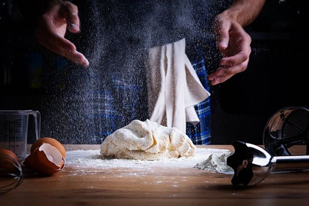 Mužské ruce dělají těsto na pizzu, knedlíky nebo chleba. Koncept pečení. - Fotografie, Obrázek