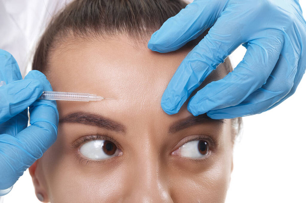 Cropped portrait of young Caucasian woman getting cosmetic injection of botox in forehead. People, cosmetology, plastic surgery and beauty concept. - Fotoğraf, Görsel